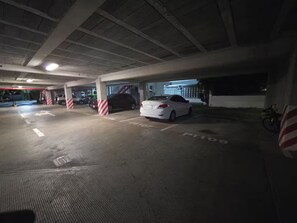 Eine Tiefgarage mit Betonpfeilern, gekennzeichneten Parkplätzen und einem am Rand abgestellten Motorrad.