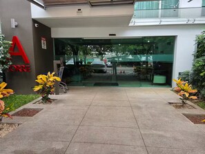 A modern building entrance with a glass door, a red sign, and potted plants. - Blissful Breeze Retreat with Pool & Workspace (Barreal)