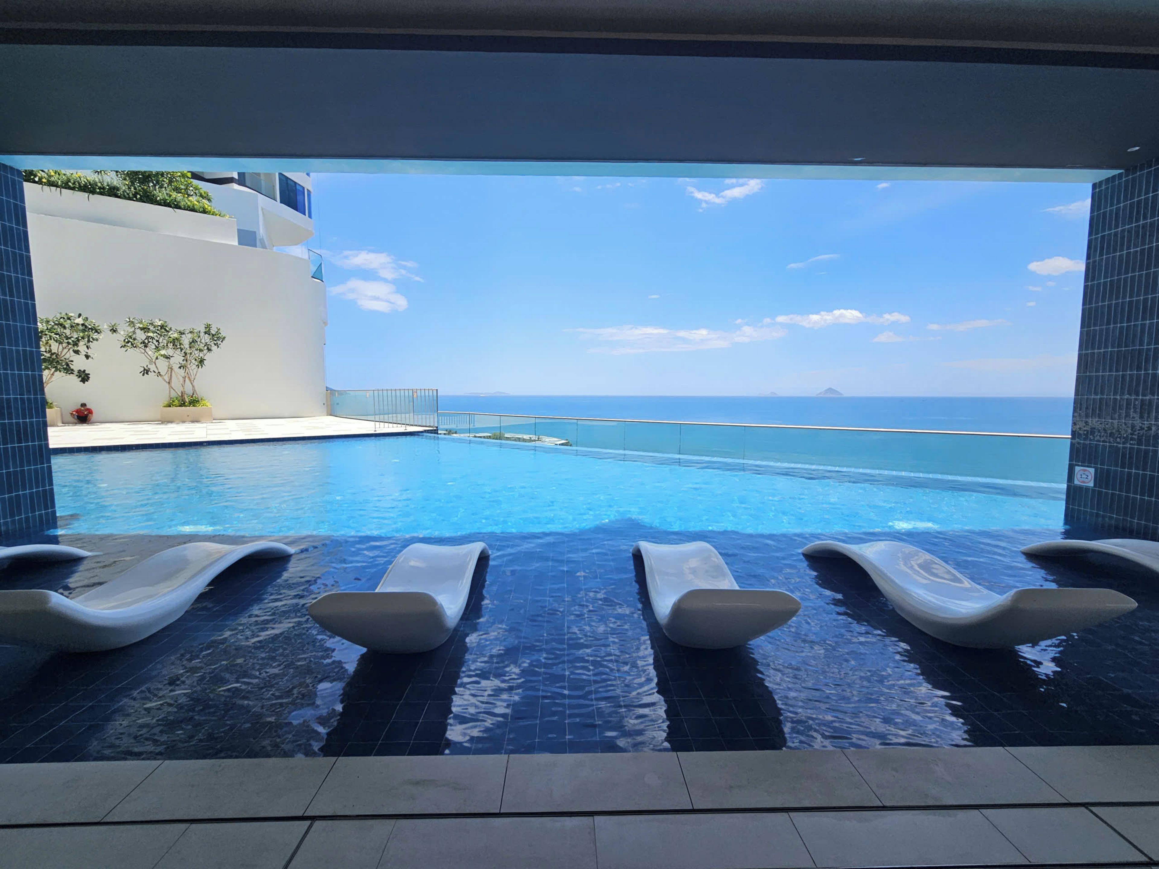 Ein Pool ohne Ende mit Liegestühlen, freier Meerblick und modernes architektonisches Design.