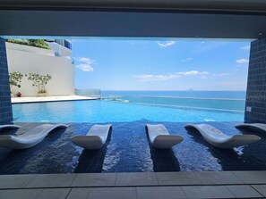 An infinity pool with lounge chairs, a clear view of the sea, and a modern architectural design. - The Paramount Apartment Nha Trang (Bac Nha Trang)
