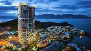 A high-rise hotel with multiple floors, a waterfront view, and a surrounding residential area with small houses.