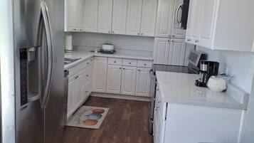 Een moderne keuken met witte kastjes, roestvrijstalen apparatuur en een houten vloer.