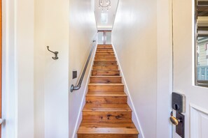 Eine Holztreppe mit Handlauf, weißen Wänden und einer Tür mit Schlüsselloch.