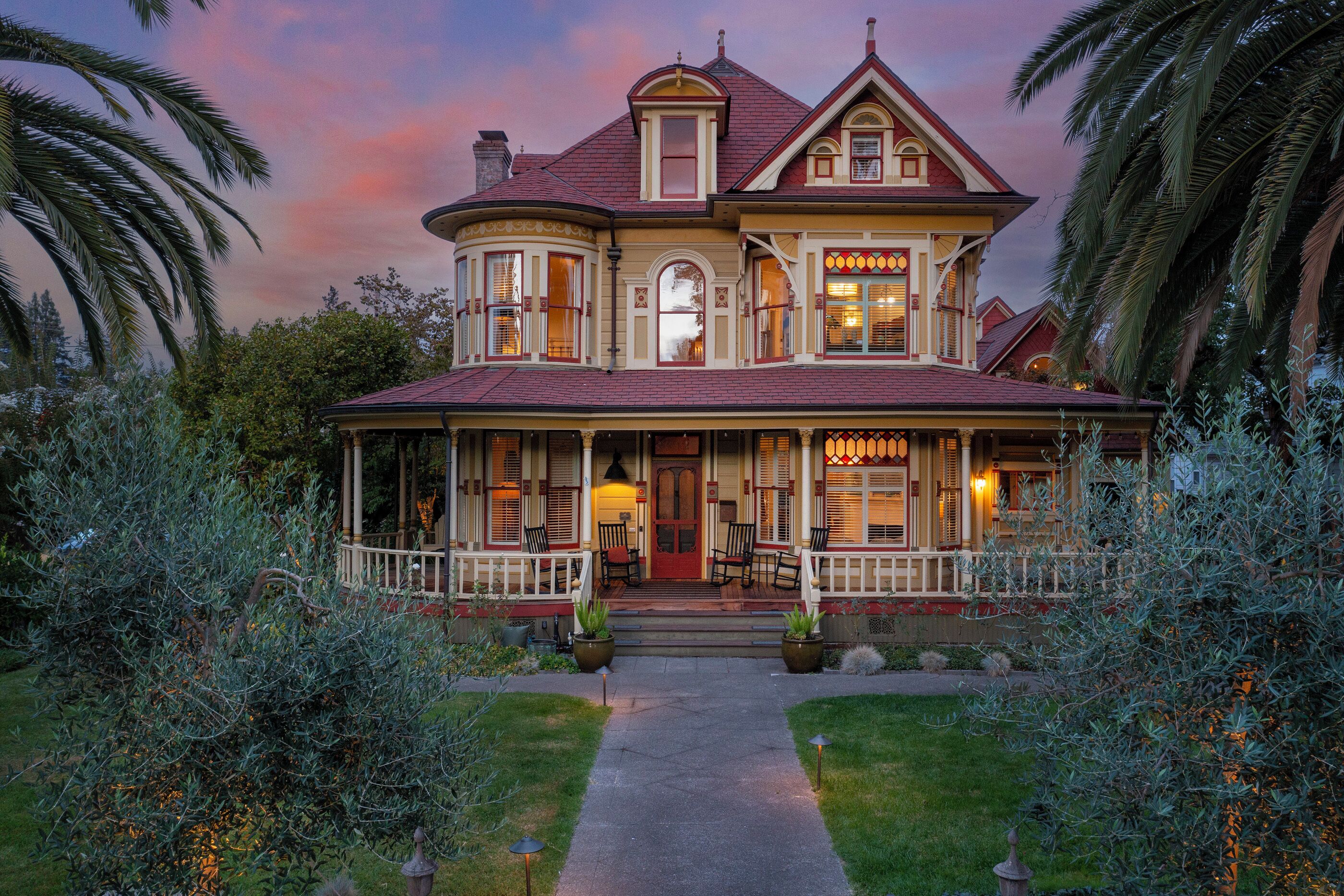 A two-story house with a wrap-around porch, a bay window, and a front door with a red doorbell.