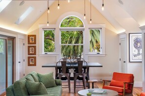 Ein Essbereich mit Tisch und Stühlen, ein grünes Sofa und ein roter Sessel.