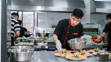 A kitchen with stainless steel appliances and a chef preparing food.
