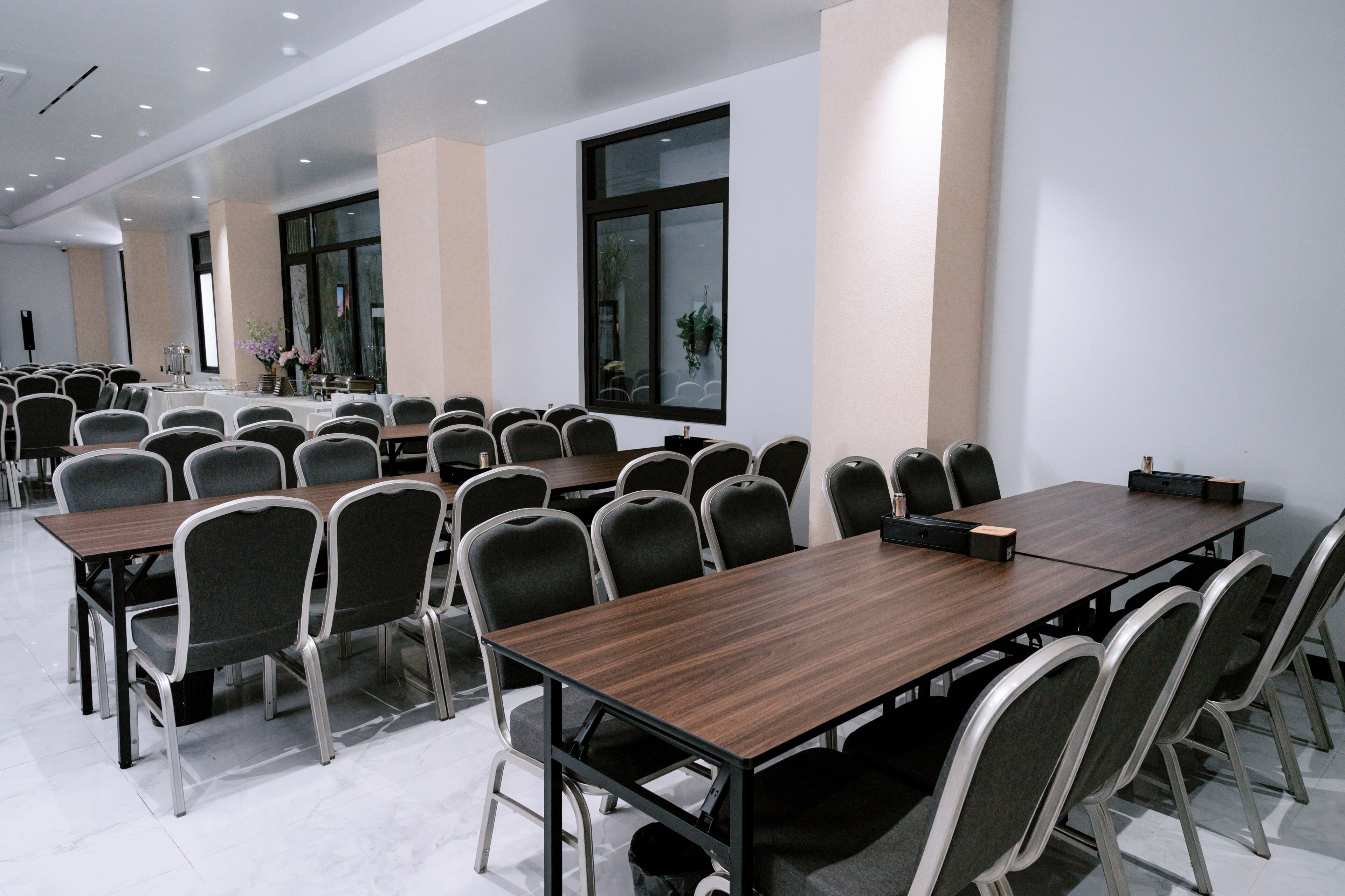 Une salle de conférence dotée de plusieurs tables et chaises, de grandes fenêtres et d’un aménagement épuré et moderne.
