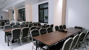 A conference room with multiple tables and chairs, large windows, and a clean, modern design.