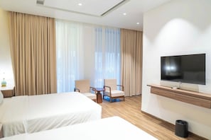 Hotellihuone, jossa on kaksi sänkyä, televisio, työpöytä ja tuoli.