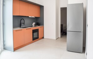 Eine moderne Küche mit Einbauofen, Edelstahlkühlschrank und grauer Rückwand.