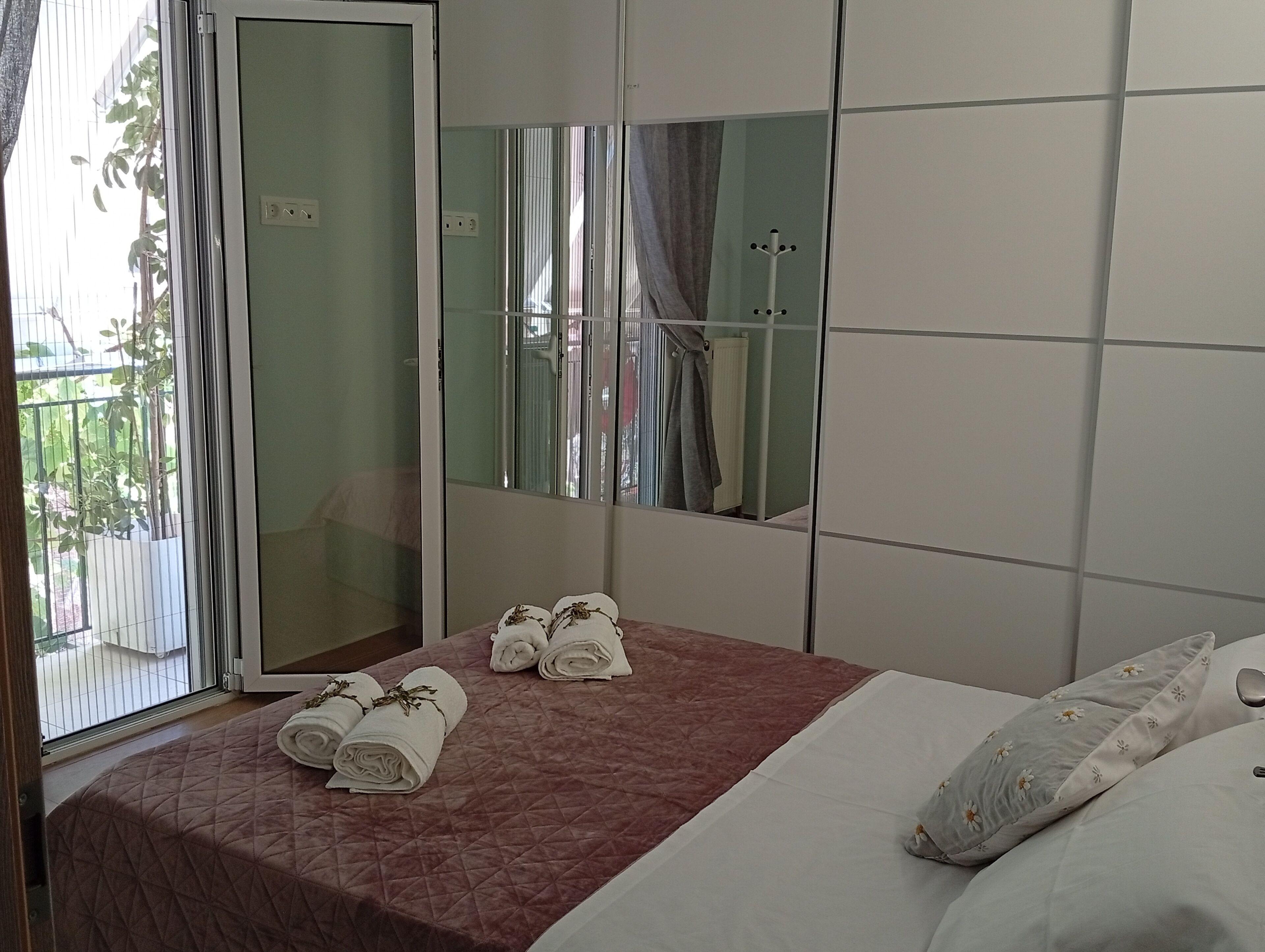 Een hotelkamer met een bed, een spiegel en een raam met uitzicht op groen.