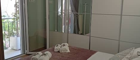 Habitación de hotel con cama, espejo y ventana con vistas a zonas verdes.