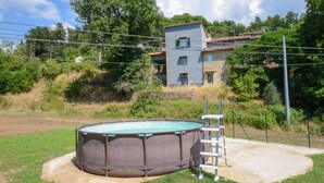 A swimming pool with a ladder, surrounded by a grassy area and a house in the background. - Amazing home in Arcidosso (Arcidosso)