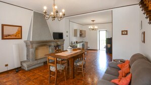 A living room with a fireplace, a dining table, and a sofa. - Amazing home in Arcidosso (Arcidosso)