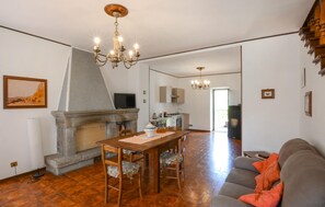 A living room with a fireplace, a dining table, and a sofa. - Amazing home in Arcidosso (Arcidosso)
