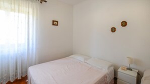 A bedroom with a single bed, a nightstand, a lamp, and a window with sheer curtains. - Amazing home in Arcidosso (Arcidosso)