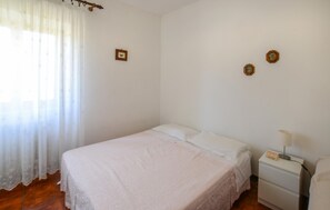 A bedroom with a single bed, a nightstand, a lamp, and a window with sheer curtains. - Amazing home in Arcidosso (Arcidosso)