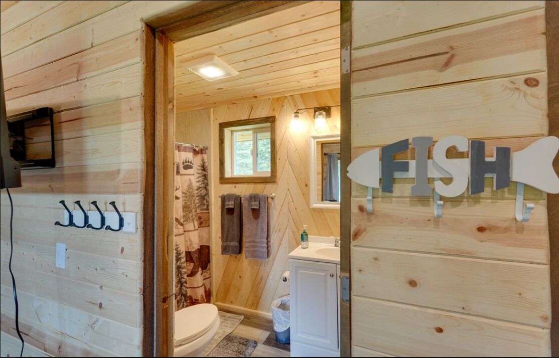 Un baño de cabaña de madera con inodoro, lavabo y toallero.
