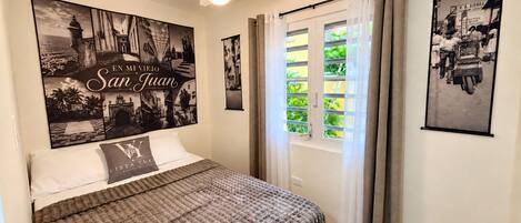 Ein Schlafzimmer mit einem Bett, einem Deckenventilator und zwei gerahmten Bildern an der Wand.