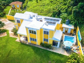 Ein mehrstöckiges, gelbes Gebäude mit Schwimmbecken, Solaranlage und gepflegtem Rasen.