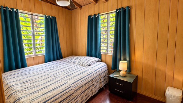 A room with a bed, a nightstand, a lamp, and a window with curtains.