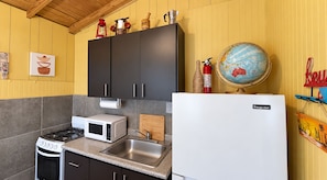 A compact kitchen with a gas stove, microwave, and a white refrigerator.