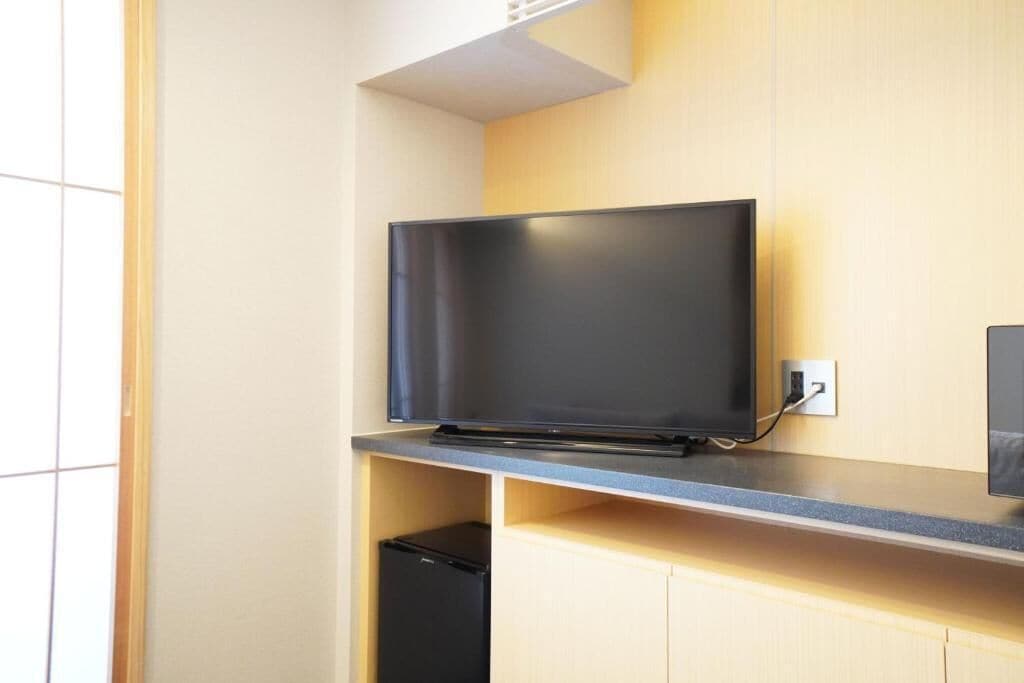 Un televisor de pantalla plana montado en la pared con un mueble de madera debajo.
