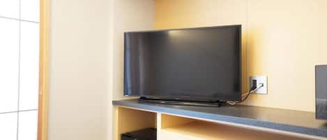 Un téléviseur à écran plat fixé au mur, avec un meuble en bois placé en dessous.