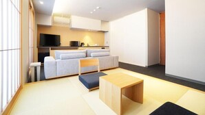 Un espacio moderno para vivir con un sofá, una mesa de madera y un televisor al fondo.