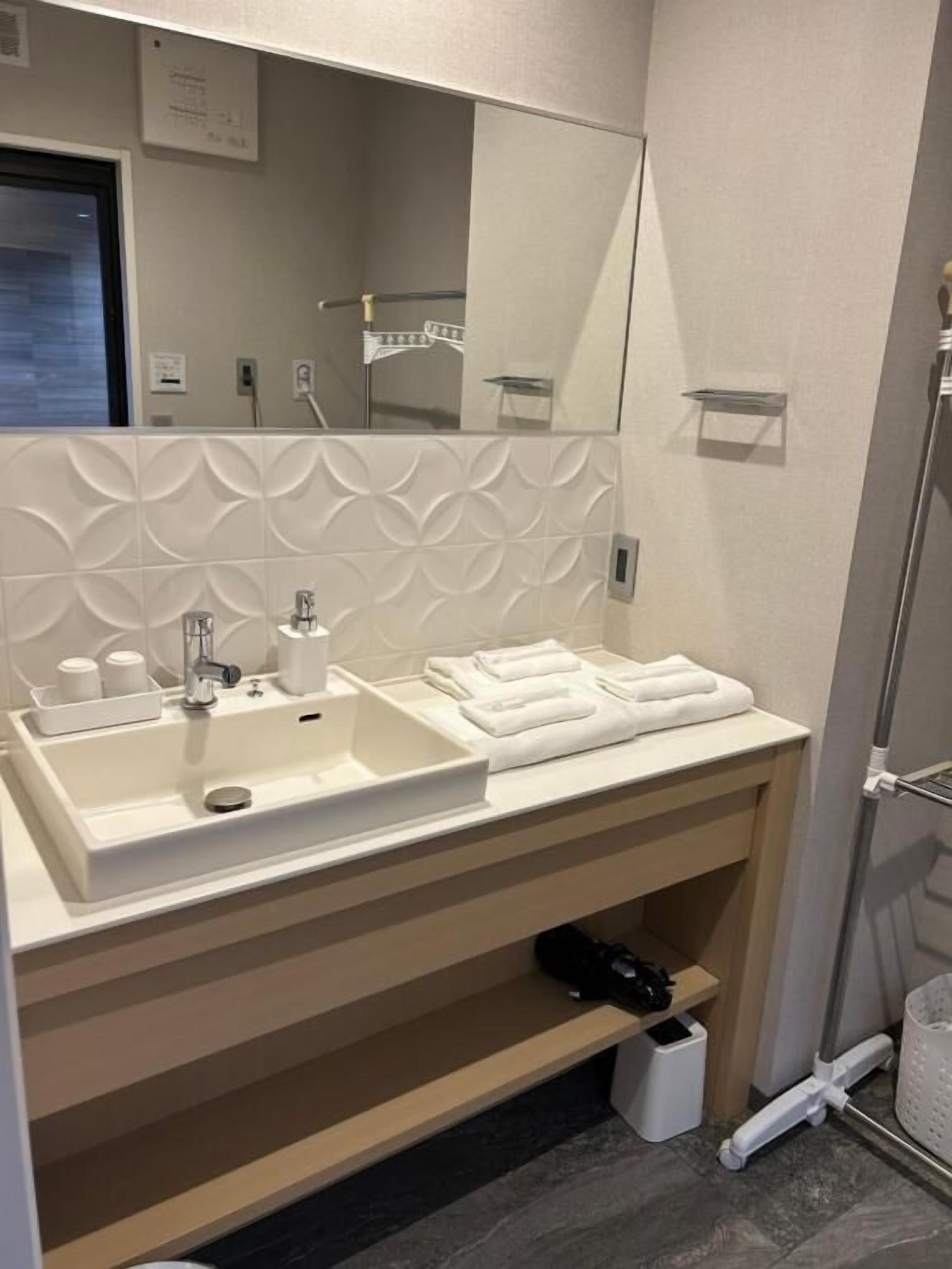 A modern bathroom with a large mirror, a sink, and a towel rack.