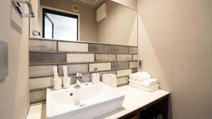 Un baño con un lavamanos blanco, un espejo y un perchero para toallas.