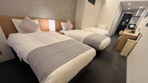 Habitación de hotel con dos camas, kitchenette pequeña y baño independiente.