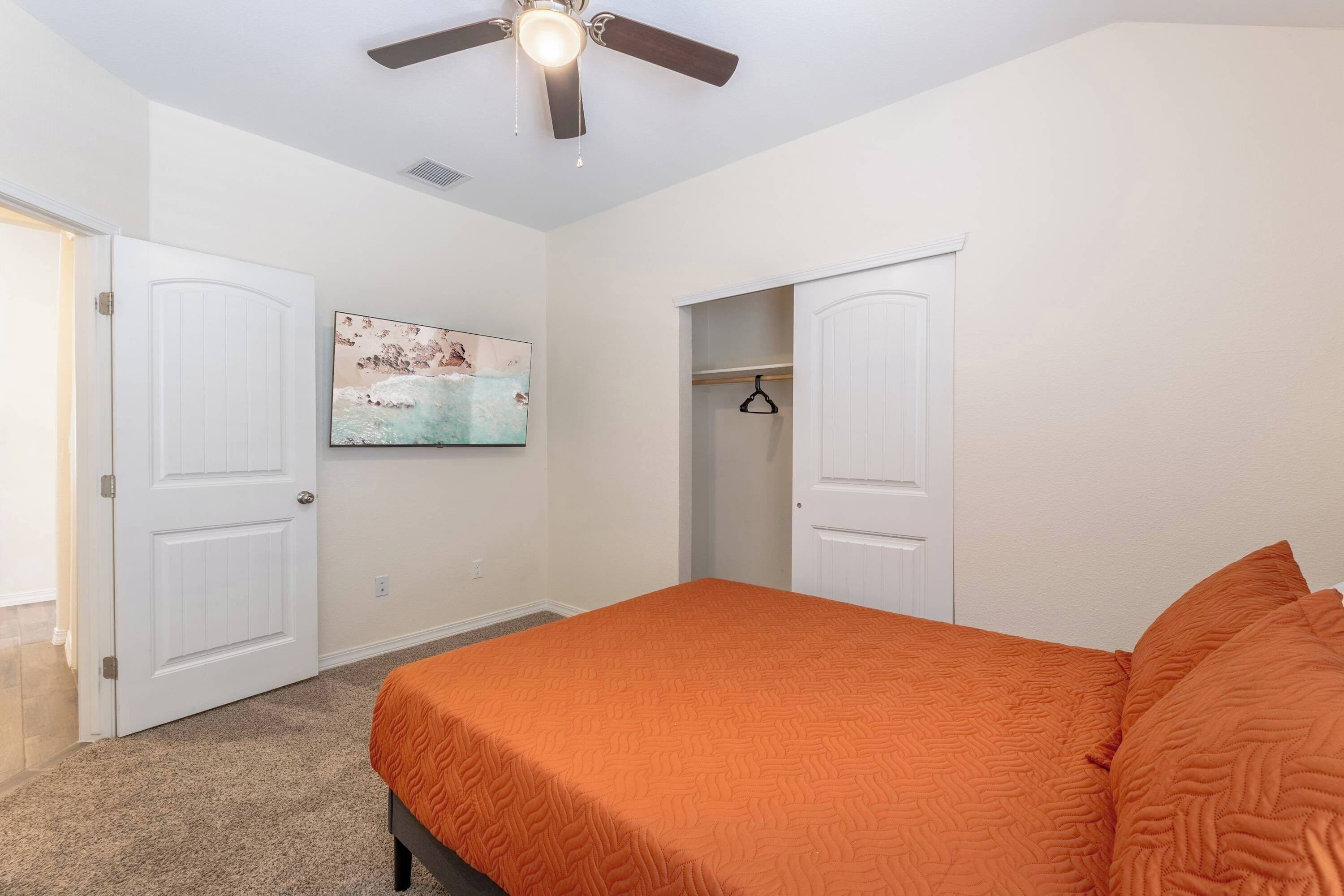A bedroom with a bed, a ceiling fan, and a door leading to a closet.