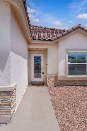 A residential building with a tiled roof, a front door with a decorative glass panel, and a window with shutters.