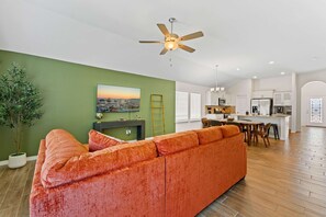 A modern living room with a sofa, a painting, and a ceiling fan.