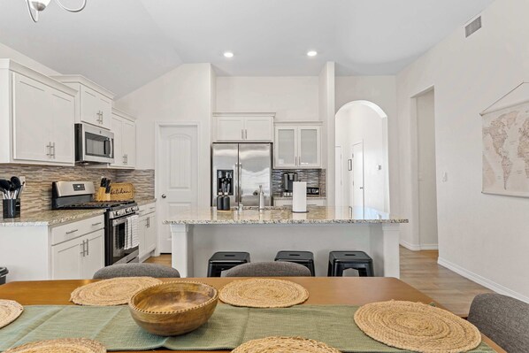 A modern kitchen with white cabinetry, stainless steel appliances, and a central island.