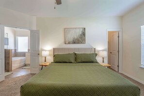 Een slaapkamer met een groot bed, twee bedlampen, een hoofdeinde en een abstract schilderij aan de muur.