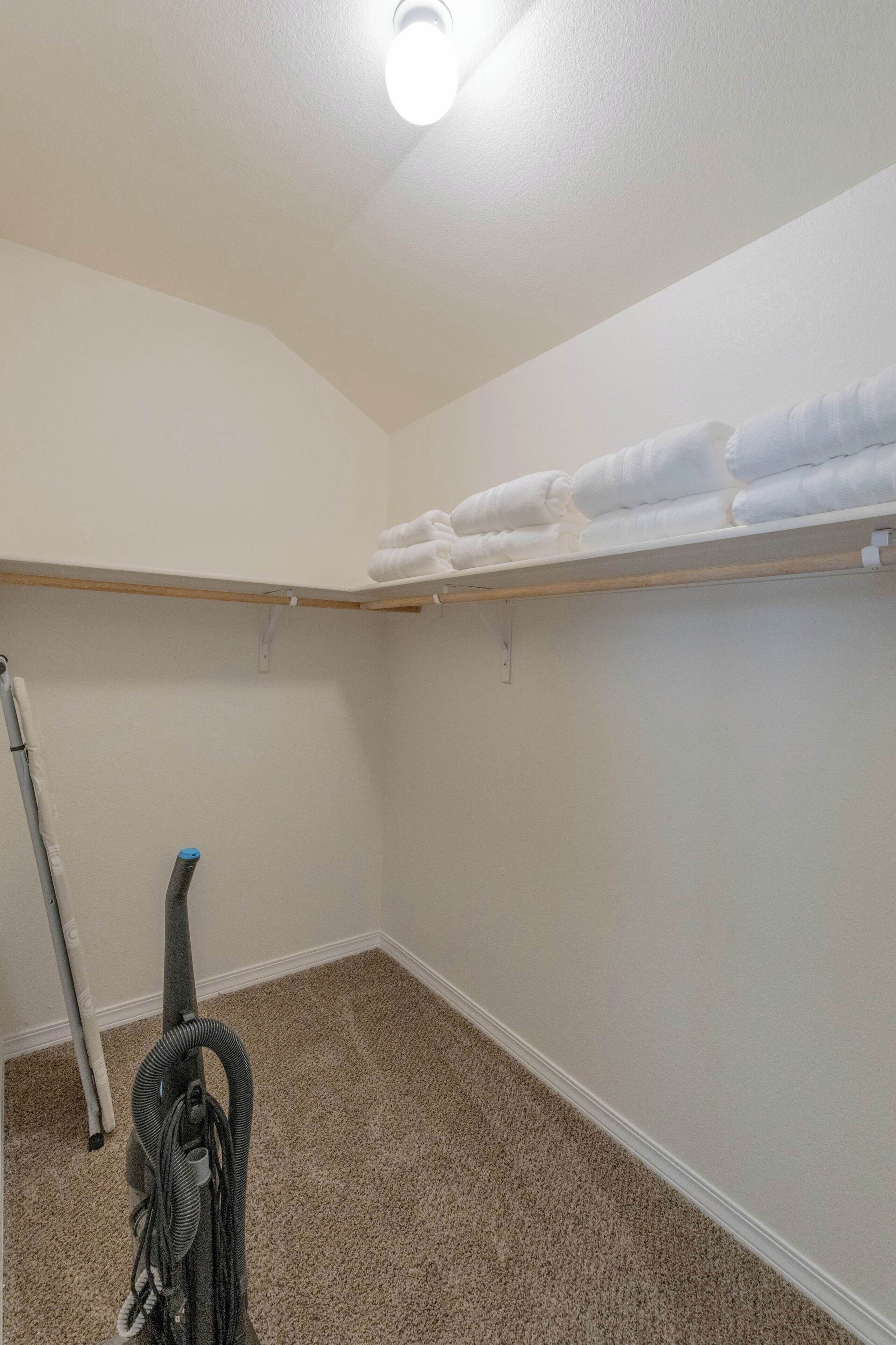 A room with a carpeted floor, a ceiling light, and a vacuum cleaner.