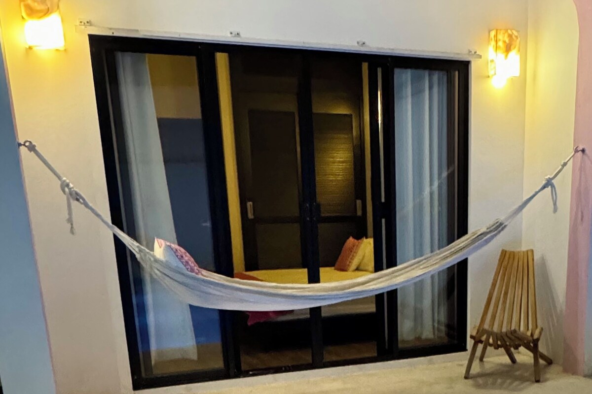 A hammock tied between two poles, a wooden easel, and a pool with blue tiles.