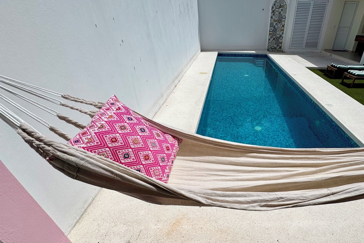 A pool area with a hammock, lounge chairs, and a small pool.