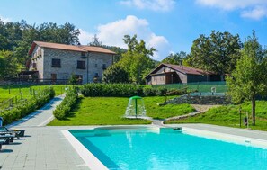 Ein Schwimmbecken mit einem steinernen Weg, der zu einem Gebäude mit rotem Dach führt.