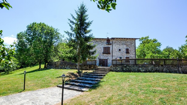 A stone building with a staircase leading to a wooden door, surrounded by a stone wall and a wooden fence. - Amazing home in Badia Tedalda (Badia Tedalda)