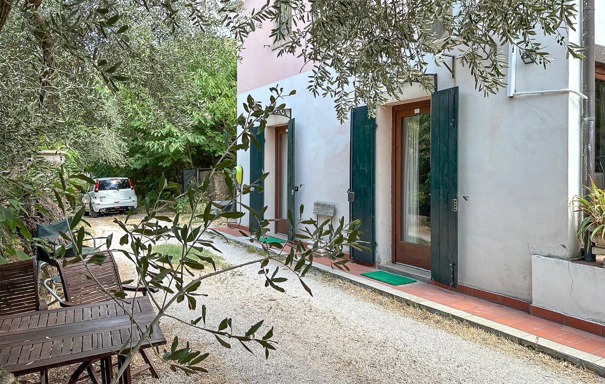 Une maison d’habitation avec une allée en gravier, une voiture blanche garée devant, et une table en bois au premier plan.