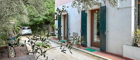 Une maison d’habitation avec une allée en gravier, une voiture blanche garée devant, et une table en bois au premier plan.