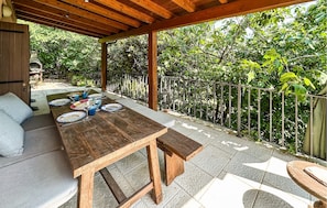 An outdoor patio with a wooden table set for dining, surrounded by a metal railing and lush greenery. - 1 bedroom nice home in Arquà Petrarca (Arquà Petrarca)