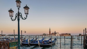 Gondolas amarradas en un muelle junto a un edificio histórico al fondo.