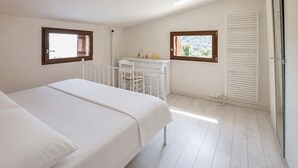 Un dormitorio con una cama, un escritorio y dos ventanas.