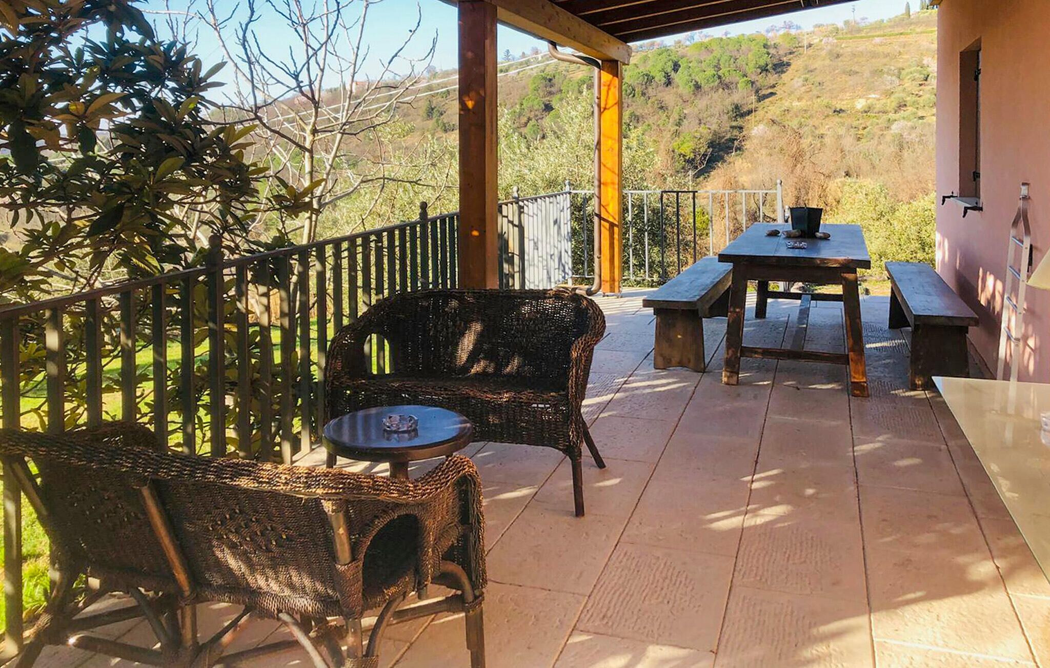 An outdoor patio with wicker furniture, a table, and benches.
