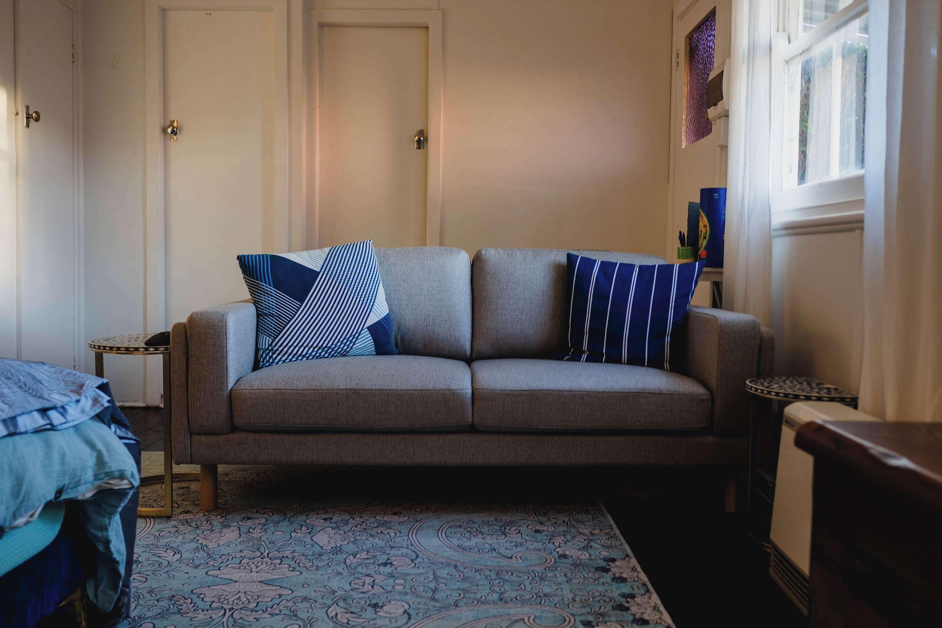 A neutral-colored sofa with patterned cushions, a patterned rug, and a small side table with a decorative item.