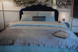 A neatly made bed with a patterned bedspread, pillows, and a bedside lamp. - The Garden Flat - Charming Studio (Orange)